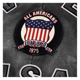 A circular embroidered patch featuring an American flag design with the text 'ALL AMERICANS' and 'ESTABLISHED 1975' on a black leather background.