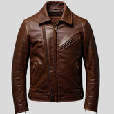 A brown leather motorcycle jacket with an asymmetrical zipper, zippered chest pocket, and zippered hand pockets, shown against a solid gray background.