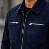 A close-up of a person wearing a dark navy blue zip-up jacket with silver zippers on the chest over a black shirt.