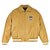 A tan leather varsity-style jacket with a front zipper, ribbed knit collar, cuffs, and hem, featuring a black, white, and red embroidered 'ANJIRE' graphic on the left chest, displayed on a clean white background.