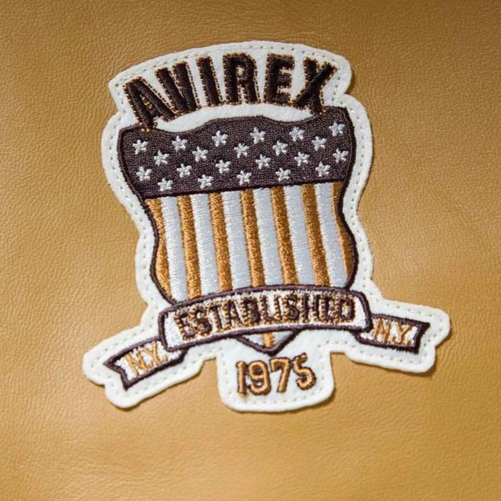 An embroidered shield-shaped patch with the word 'AWIREX' at the top, a dark brown top section with white stars, vertical tan and white stripes, a banner reading 'EST. 1975', and 'N.