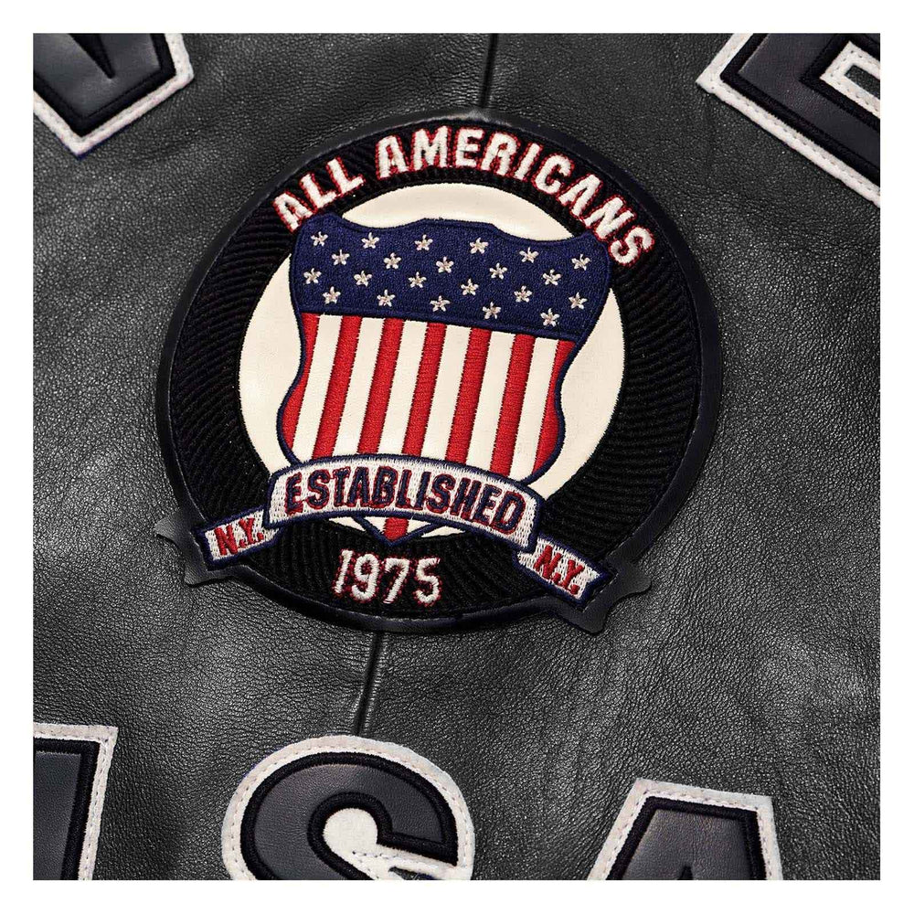 A circular embroidered patch featuring an American flag design with the text 'ALL AMERICANS' and 'ESTABLISHED 1975' on a black leather background.