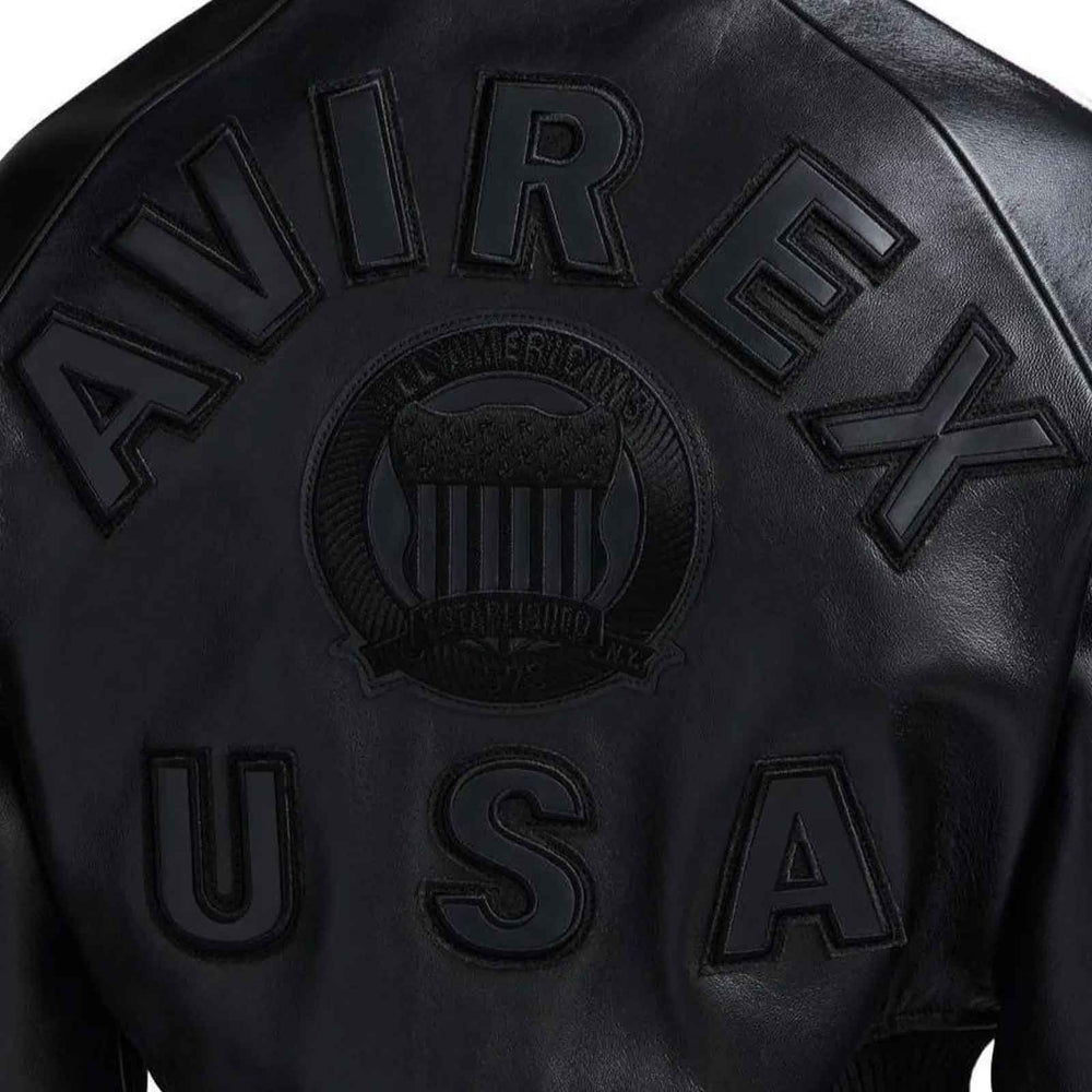 Close-up of the back of a black leather jacket featuring embossed lettering that reads 'AVIREX' and 'USA' with a central crest emblem.