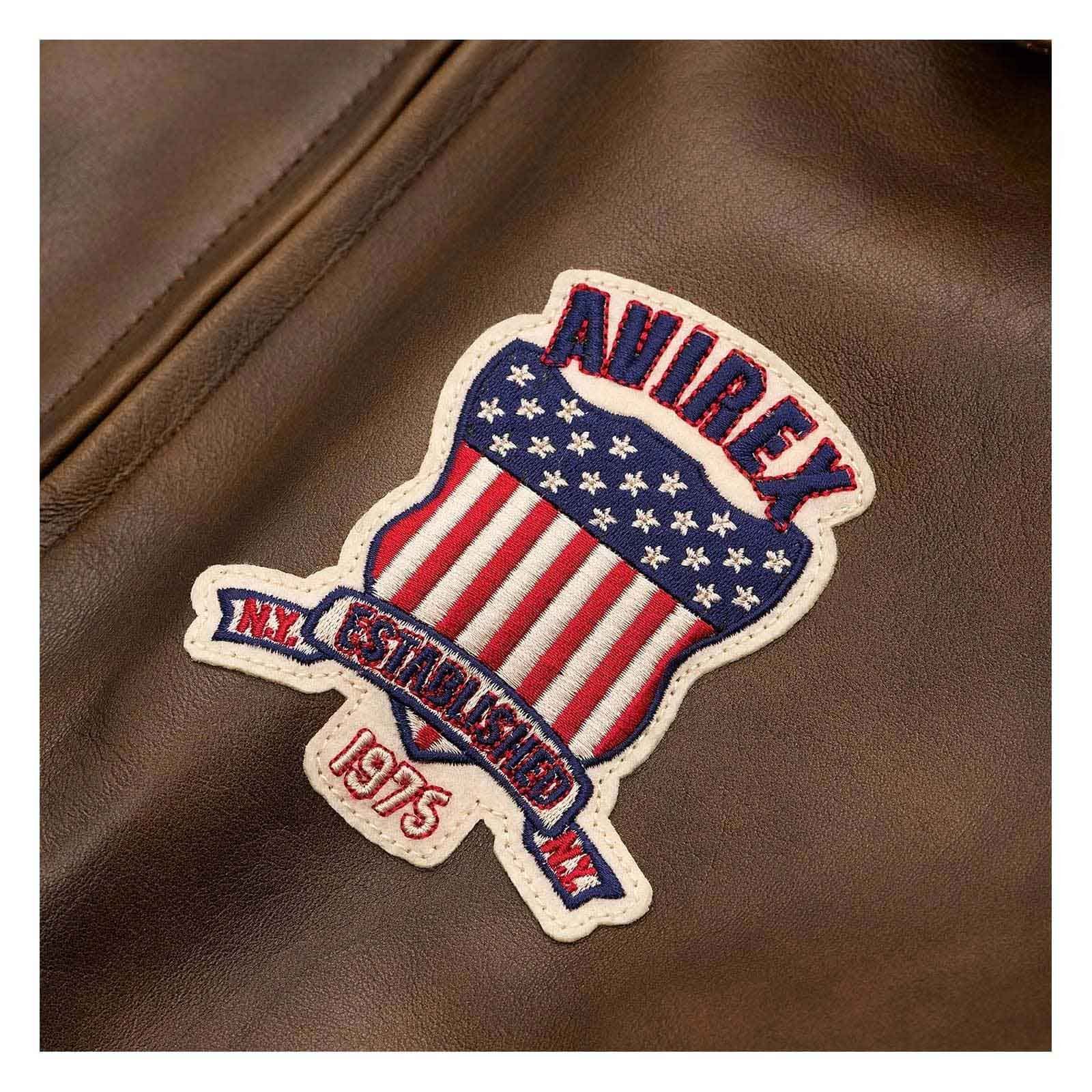 A close-up of a brown leather jacket featuring a decorative embroidered patch with the brand name 'AUREX', an American flag motif, and 'EST. 1975'.