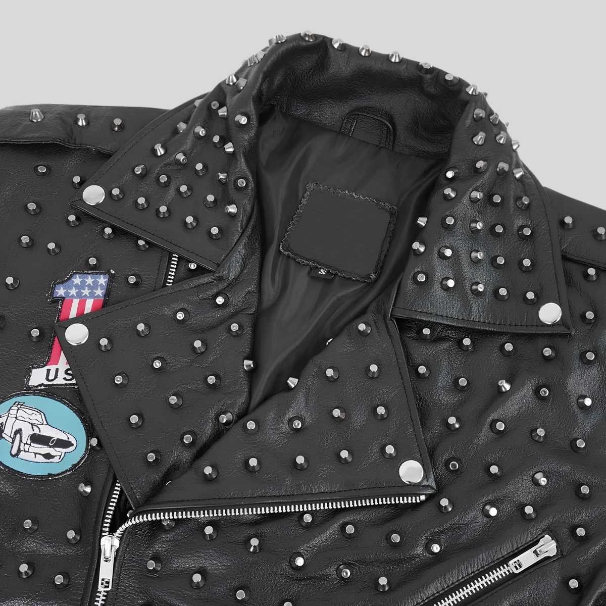 Close-up of a black leather motorcycle jacket covered in silver studs, featuring a pointed collar, zippered front, and decorative patches on the chest.