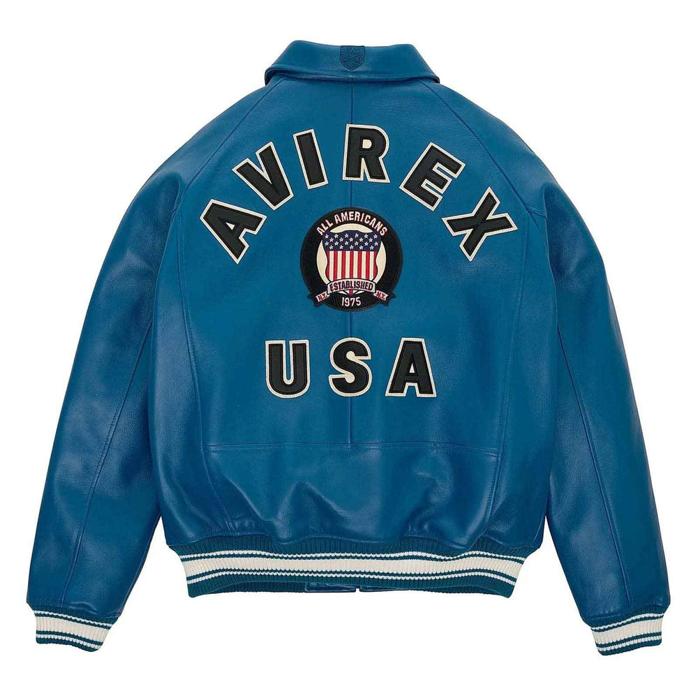 A blue leather jacket shown from the back, featuring 'AVIREX USA' and an 'All Americans 1915-1945' crest patch in large varsity-style lettering. The jacket has white and navy striped ribbed cuffs and hem.