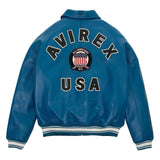 A blue leather jacket shown from the back, featuring 'AVIREX USA' and an 'All Americans 1915-1945' crest patch in large varsity-style lettering. The jacket has white and navy striped ribbed cuffs and hem.