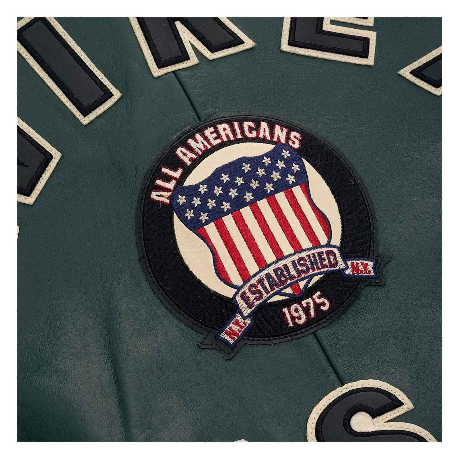 Close-up of a dark green embroidered sports jersey patch featuring an American flag design with the text 'ALL AMERICANS', 'ESTABLISHED N.Y.