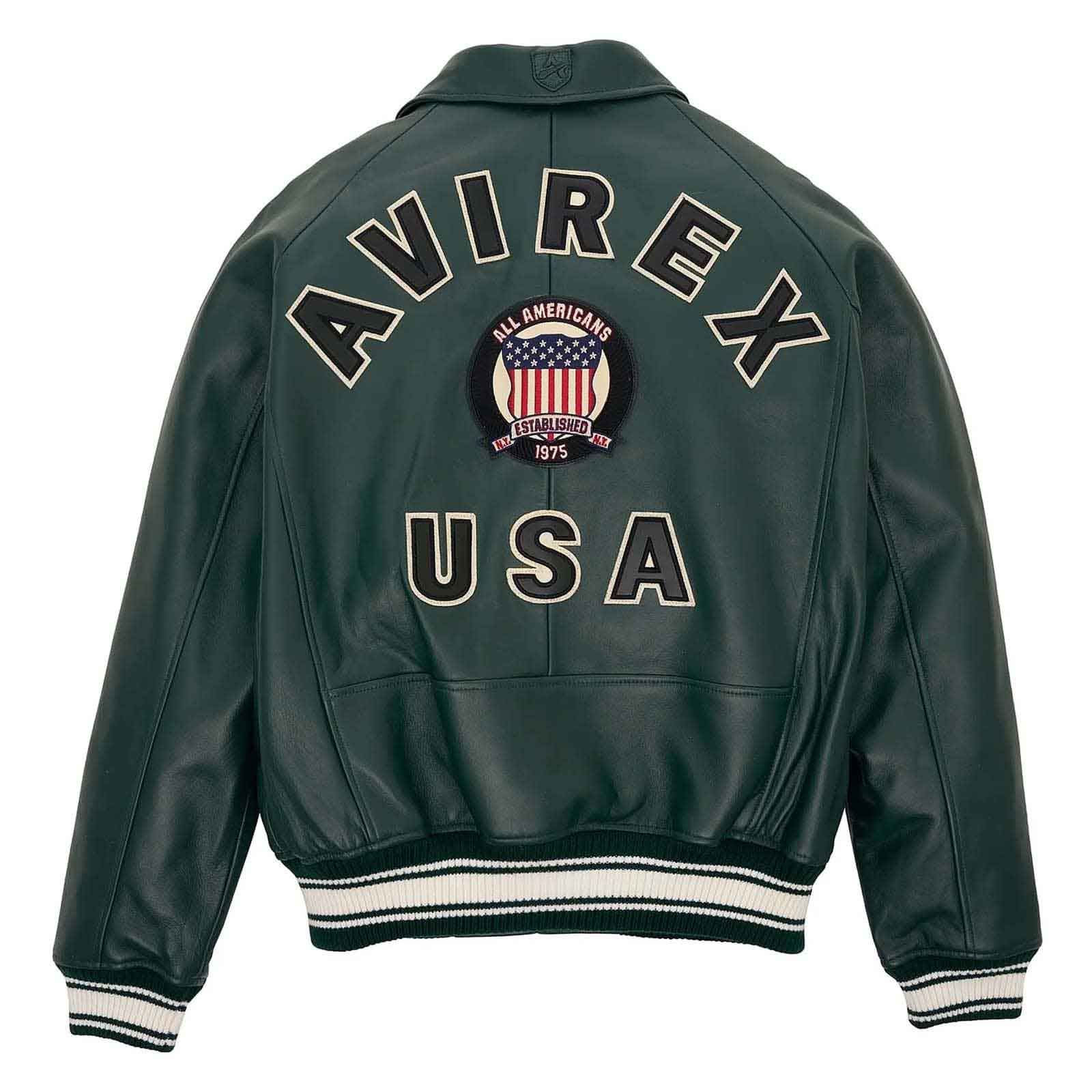 A dark green leather jacket shown from the back, featuring 'AVIREX USA' and an 'All Americans 1975' patch embroidered on the back, with striped ribbed cuffs and hem.