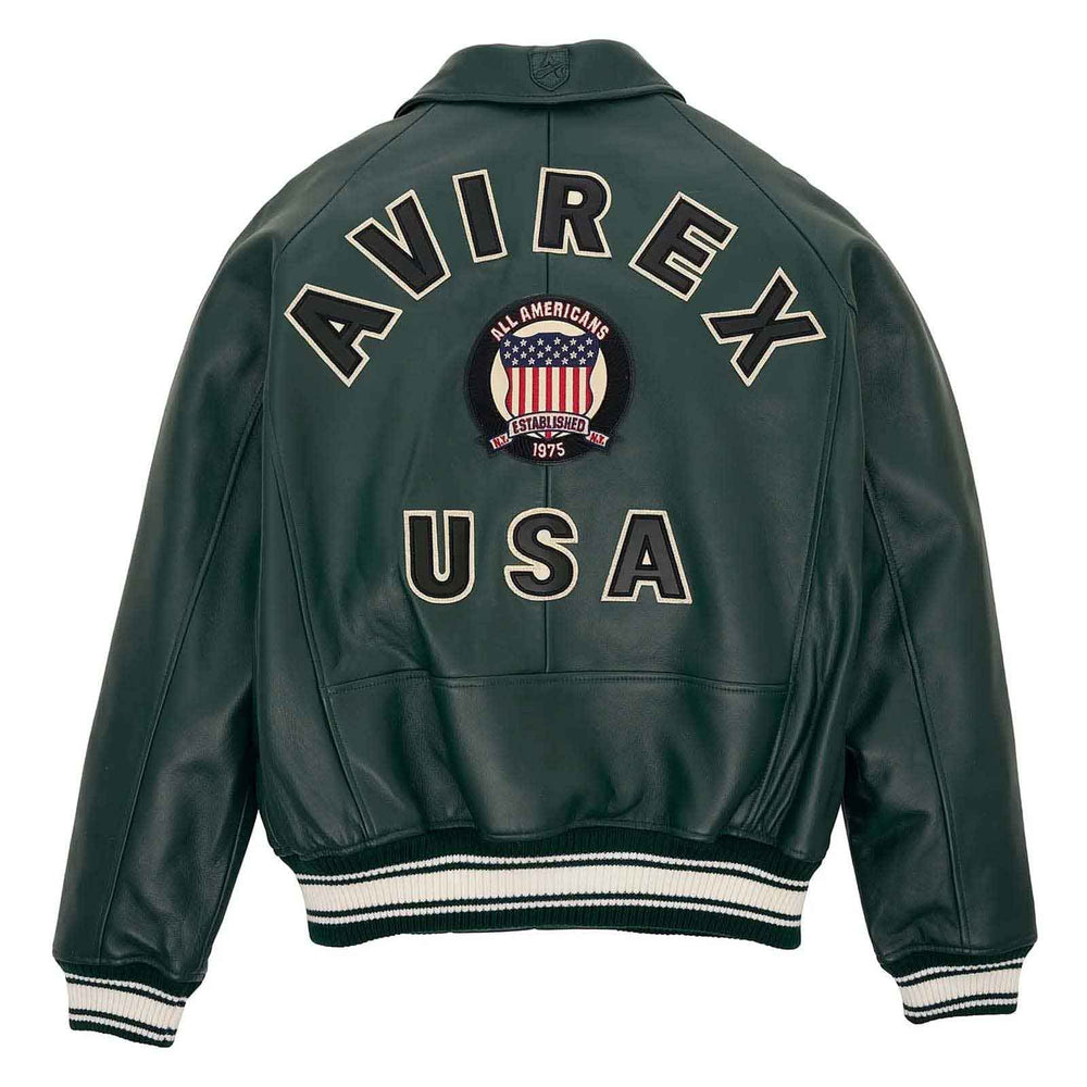 A dark green leather jacket shown from the back, featuring 'AVIREX USA' and an 'All Americans 1975' patch embroidered on the back, with striped ribbed cuffs and hem.