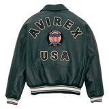 A dark green leather jacket shown from the back, featuring 'AVIREX USA' and an 'All Americans 1975' patch embroidered on the back, with striped ribbed cuffs and hem.