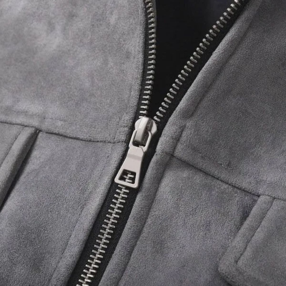 Close-up of a gray suede or micro-suede zip jacket with a silver metal zipper and pull tab.