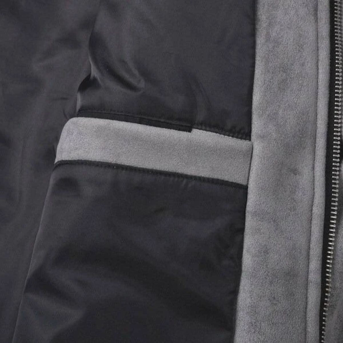 Close-up detail of a dark gray or black puffer jacket showing a horizontal light gray stripe, a vertical gray fleece or suede-like trim, and a zipper.