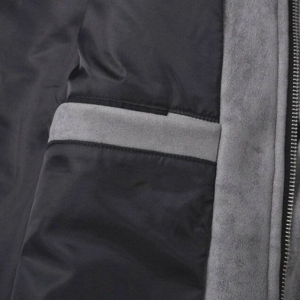 Close-up detail of a dark gray or black puffer jacket showing a horizontal light gray stripe, a vertical gray fleece or suede-like trim, and a zipper.