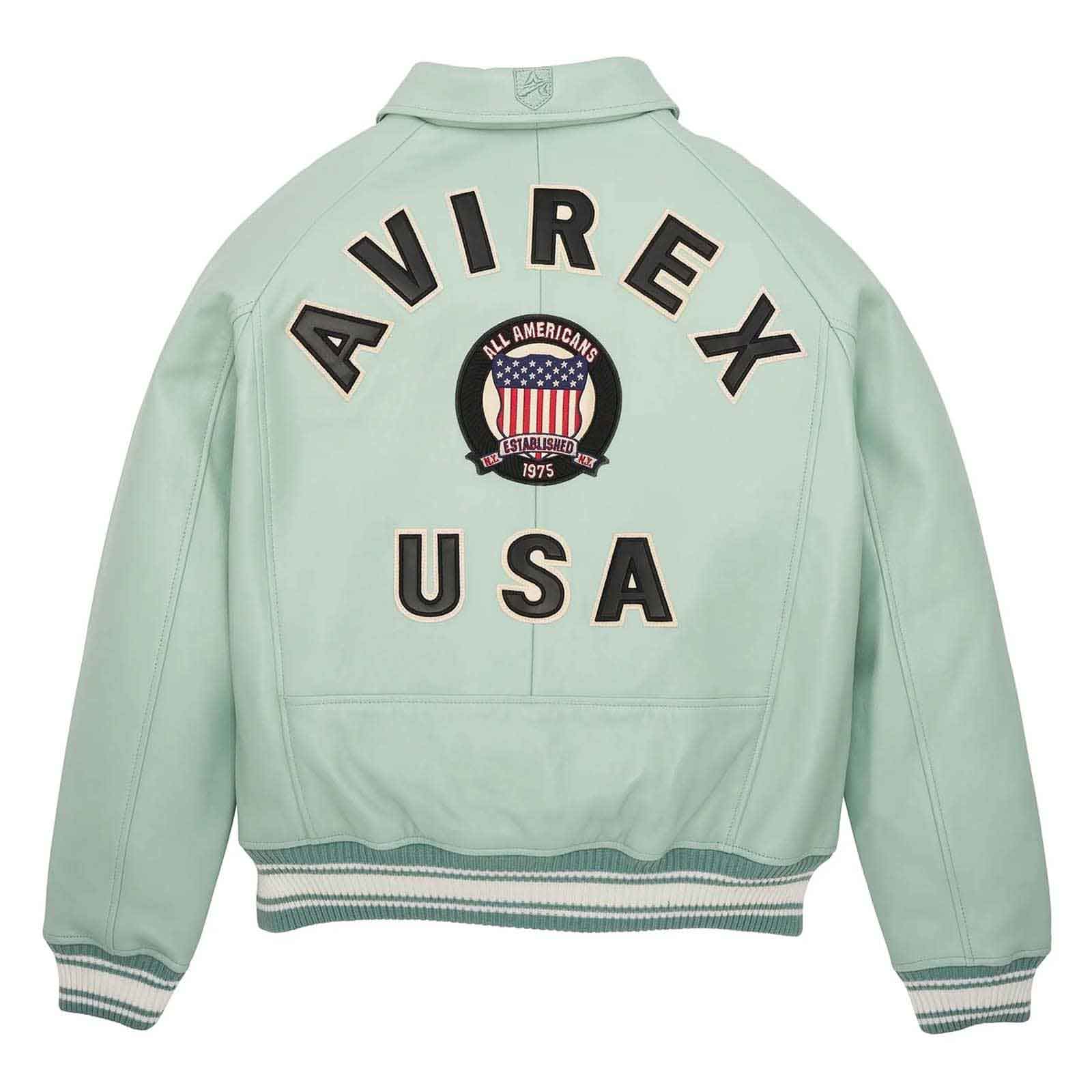 A mint green leather jacket shown from the back, featuring 'AVIREX USA' and a circular 'All Americans 1975' patch on the back. The jacket has ribbed cuffs and hem with white and dark green stripes.