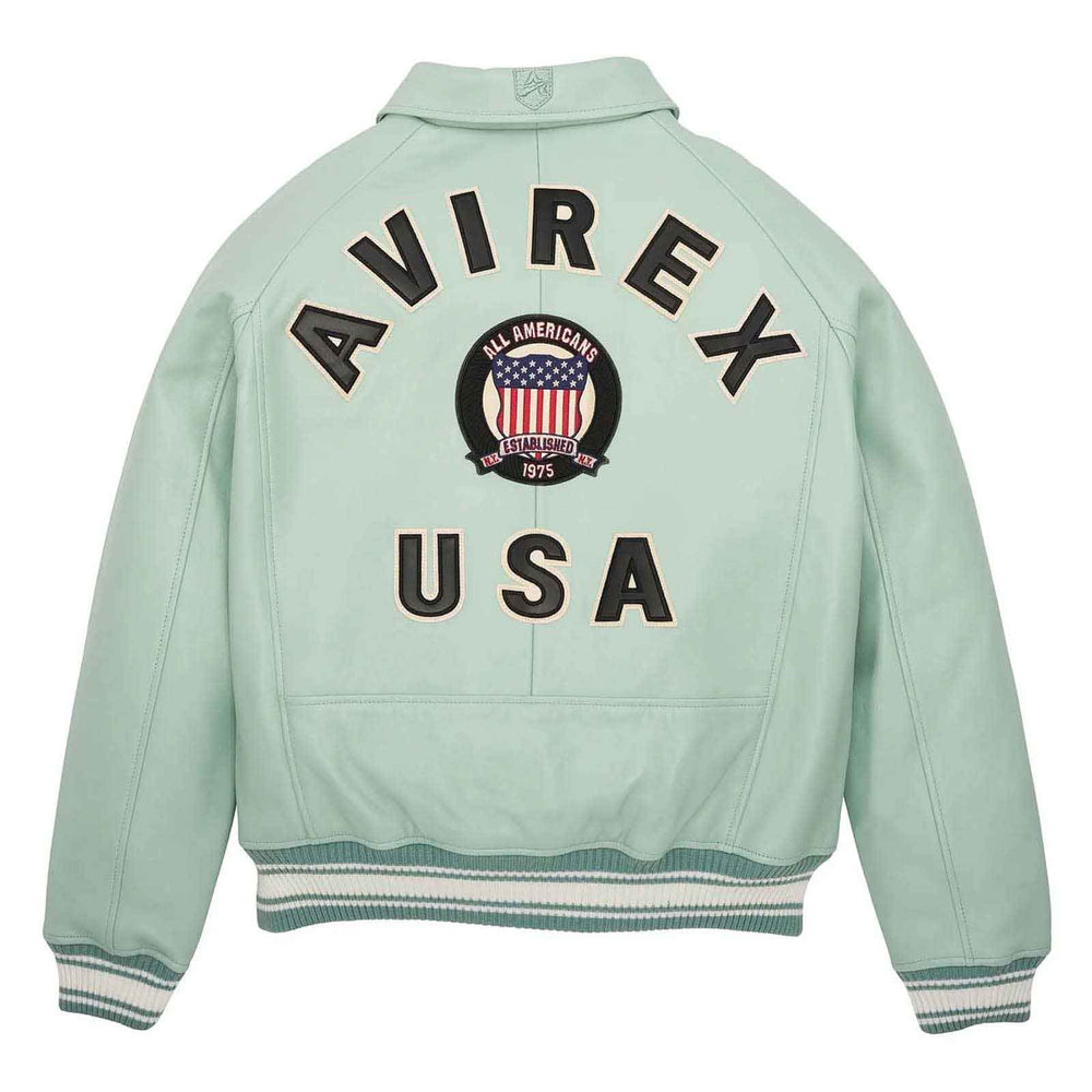 A mint green leather jacket shown from the back, featuring 'AVIREX USA' and a circular 'All Americans 1975' patch on the back. The jacket has ribbed cuffs and hem with white and dark green stripes.