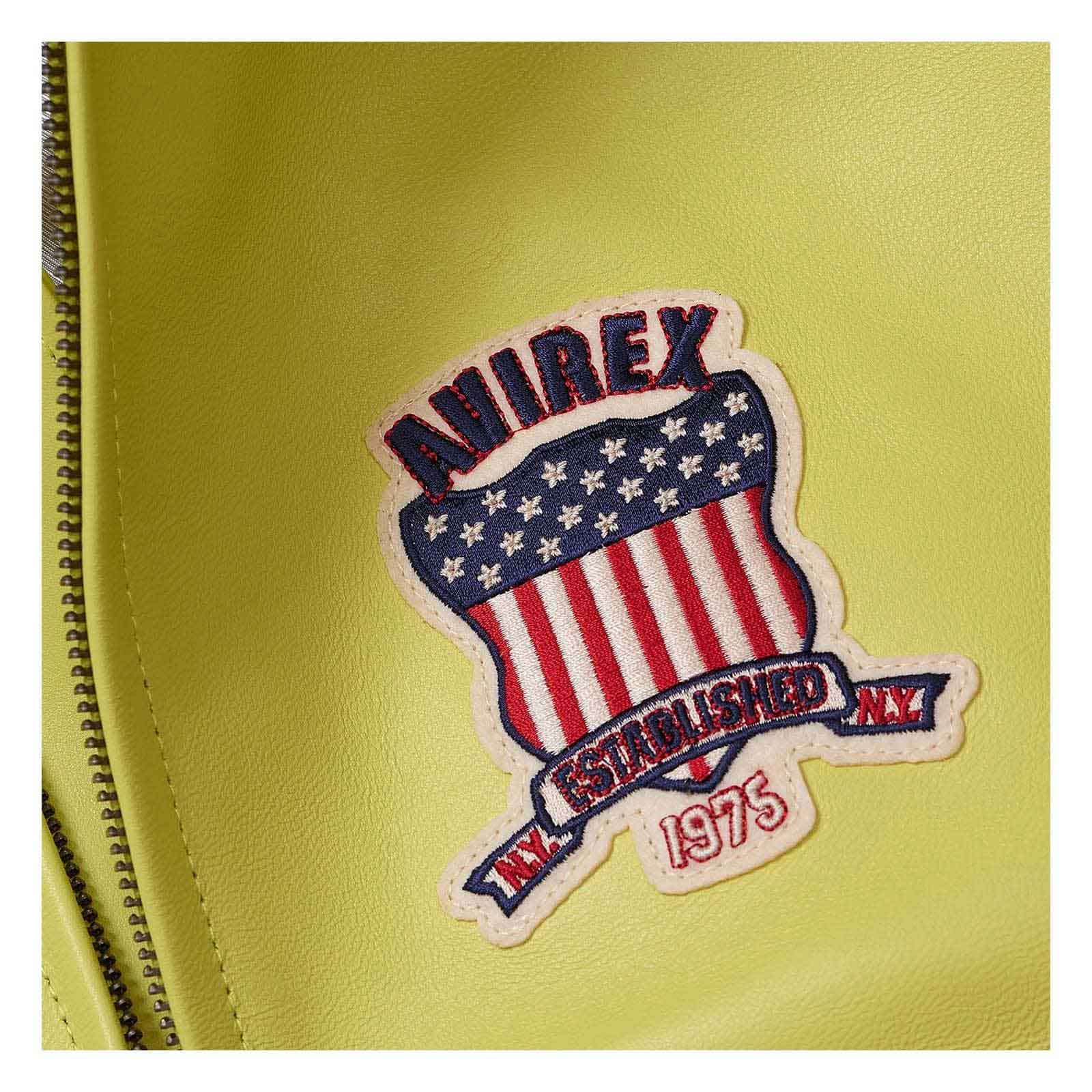 A close-up of a yellow-green faux leather surface featuring a decorative embroidered patch with the brand name 'ANIREX' and a shield design in red, white, and blue with the text 'ESTABLISHED NY 1975' and a zipper running along the left edge.
