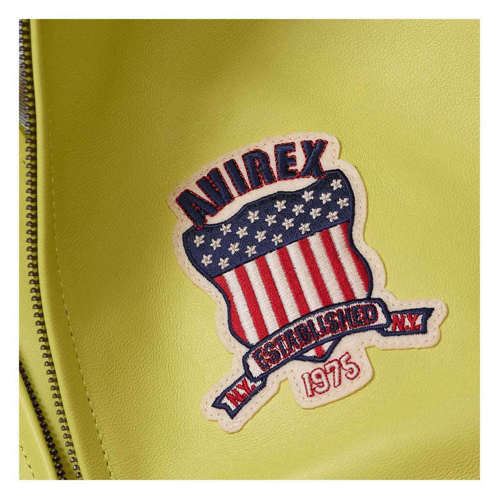 A close-up of a yellow-green faux leather surface featuring a decorative embroidered patch with the brand name 'ANIREX' and a shield design in red, white, and blue with the text 'ESTABLISHED NY 1975' and a zipper running along the left edge.