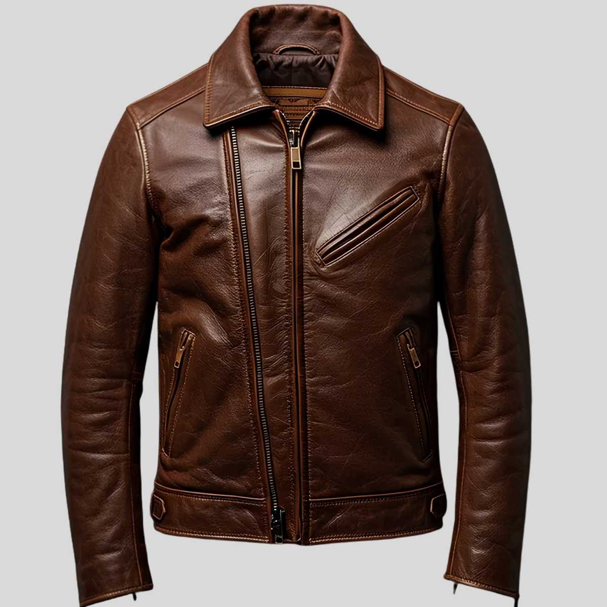 A brown leather motorcycle jacket with an asymmetrical zipper, zippered chest pocket, and zippered hand pockets, shown against a solid gray background.