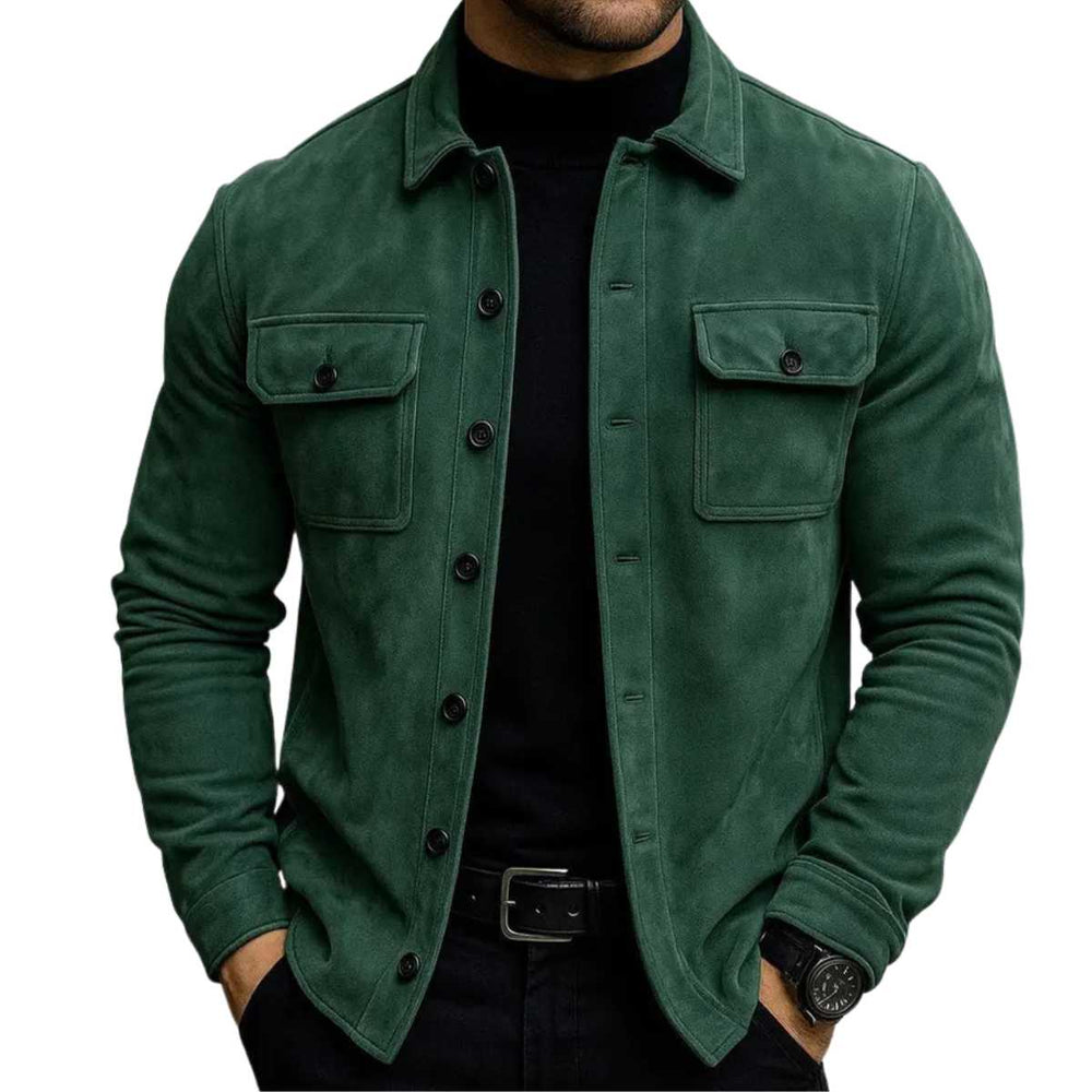 A man wearing a dark green suede-like button-up shirt jacket over a black turtleneck and black pants, shown from the chin down against a plain white background.