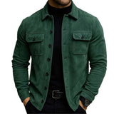 A man wearing a dark green suede-like button-up shirt jacket over a black turtleneck and black pants, shown from the chin down against a plain white background.
