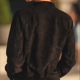 A close-up back view of a person wearing a dark brown suede or faux-suede bomber jacket with a ribbed collar and cuffs.