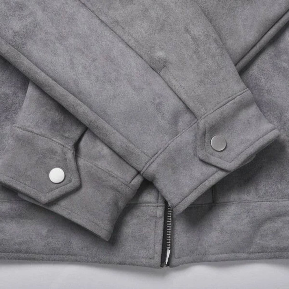 Close-up of a gray suede jacket showing the sleeve cuffs with silver snap buttons and a zipper detail at the bottom.