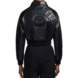 Back view of a person wearing a black leather bomber jacket with large embossed 'AVIREX USA' lettering across the back, paired with black pants, on a plain white background.