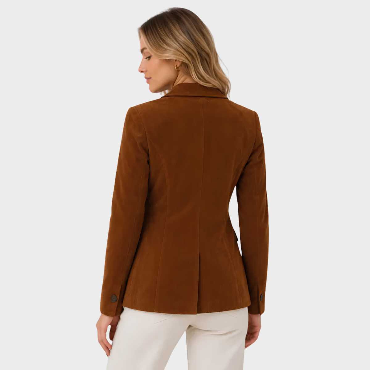 A woman shown from the back wearing a brown suede blazer and cream trousers against a light gray studio background.
