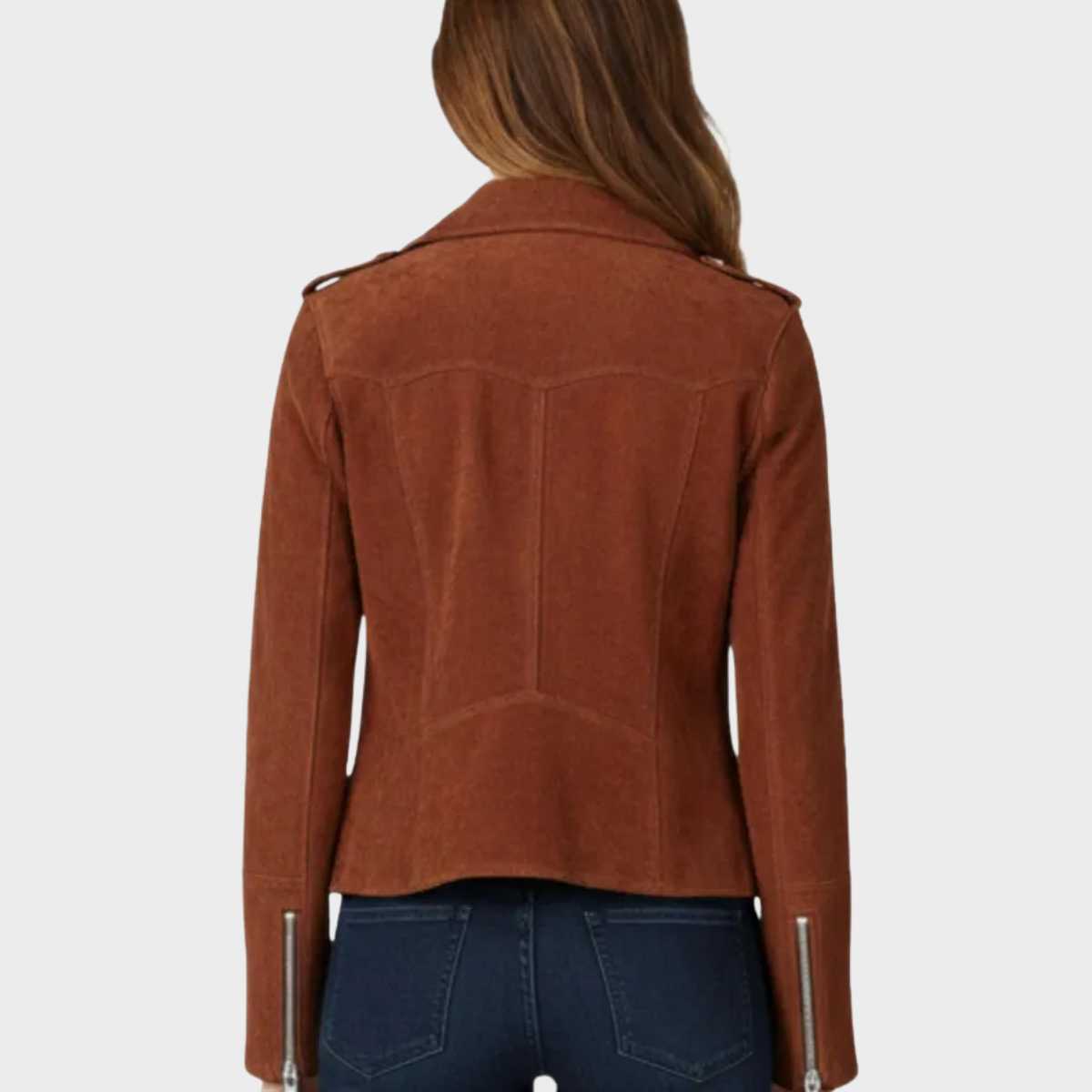 A woman viewed from the back wearing a cropped brown suede jacket with silver zipper details on the sleeves, paired with dark blue jeans, against a light gray background.