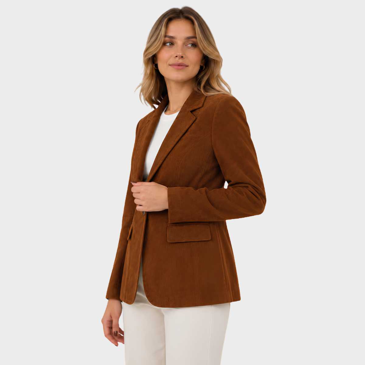 A woman modeling a brown corduroy blazer over a white top and white pants, photographed against a light gray studio background.
