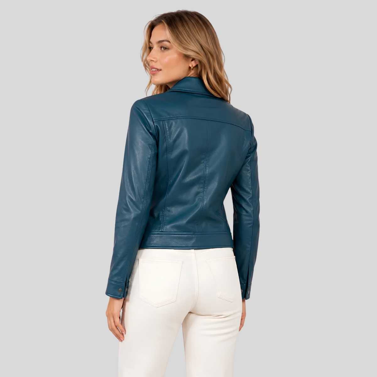 A woman shown from the back wearing a dark teal blue faux leather jacket and white pants, set against a solid light gray background.